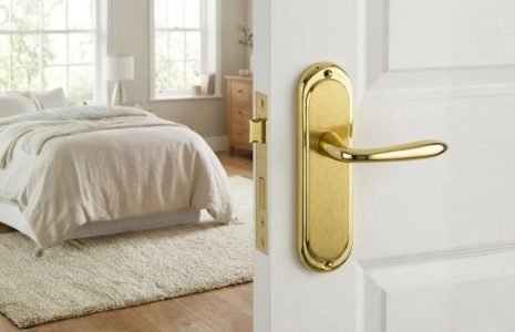 Bright bedroom with a white bed, cream rug, and a white door with a gold handle partially open, letting in light.